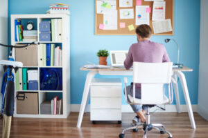 Man working in a tidy home office with light blue walls, promoting calm focus and creative thinking.