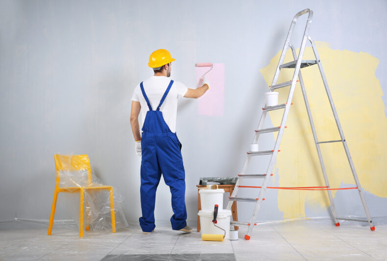 Painter applying color to wall, reflecting the impact of intentional color choices on mood and well-being.