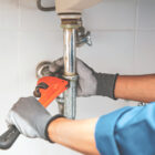Person using a wrench to repair a pipe, illustrating DIY plumbing repairs and maintenance.